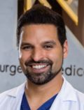 Dr. med. Nauras Abuagela ist Facharzt für Plastische, Rekonstruktive und Ästhetische Chirurgie bei der Privatklinik Berger in Frankfurt am Main, Deutschland. Er ist ein weißen Arztkittel gekleidet und lächelt ins Bild.